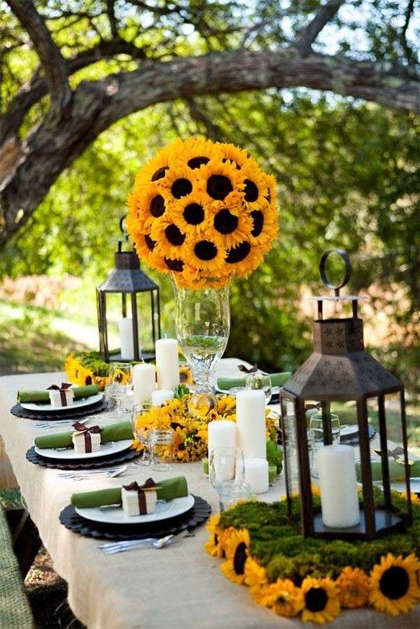 Tavola allestita in giardino con girasoli, candele e lanterne per un’occasione speciale